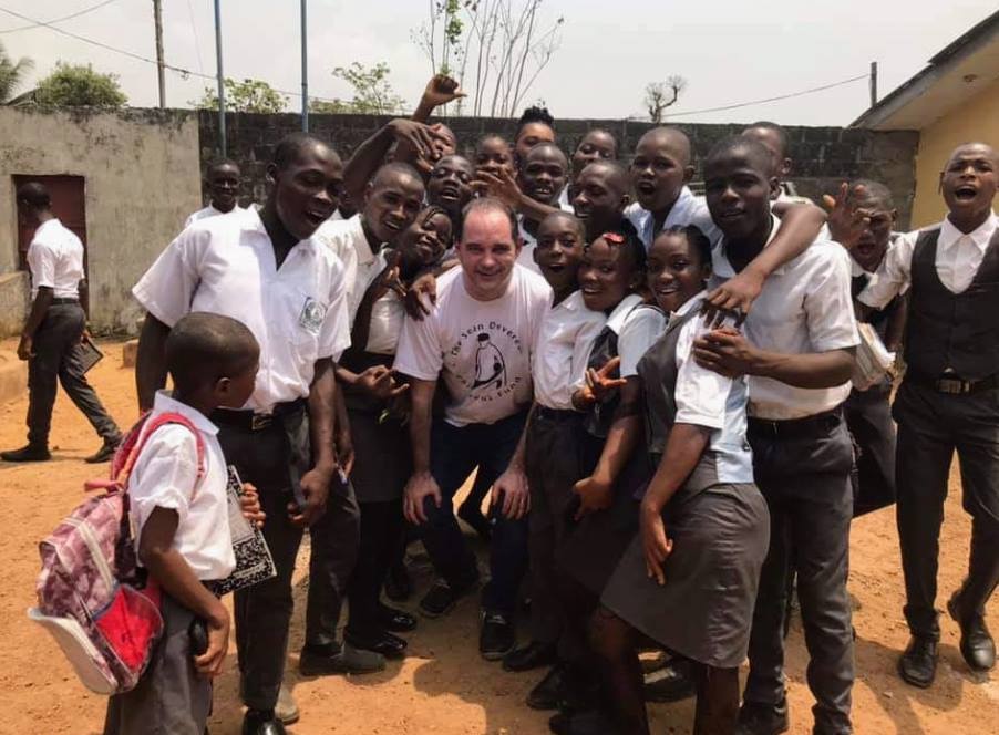 photograph of a group of children and young people surrounding Mark Chatterton MBE