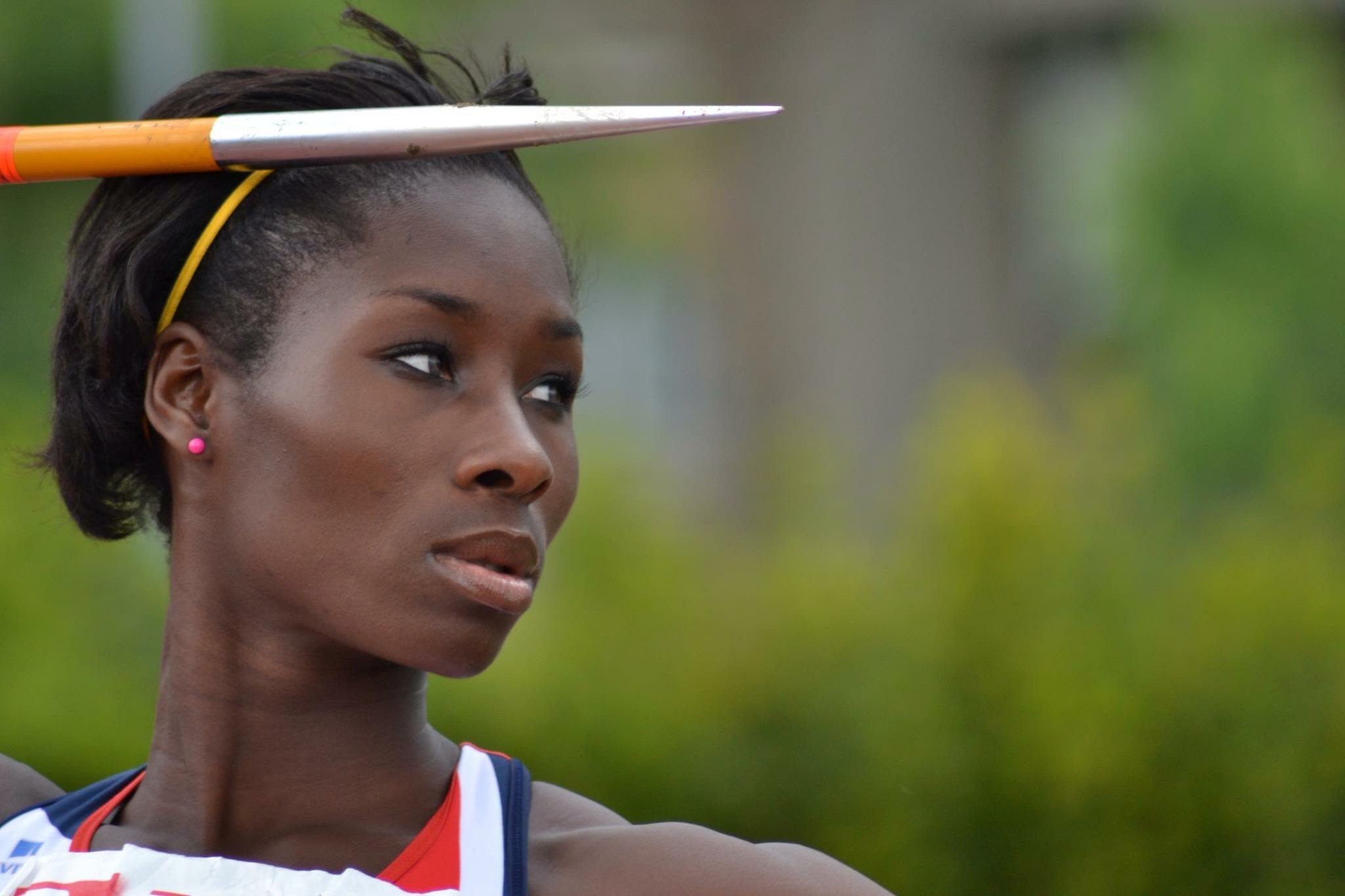 Phyllis Agbo dressed in Team GB kit, holding a javelin and looking to her left.