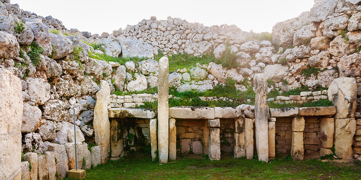 Neolithic temples in Malta, four squares entrances with boulders piled above with grass growing over the boulders