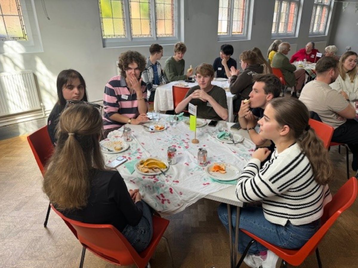 A group of freshers at a table talking and eating snacks