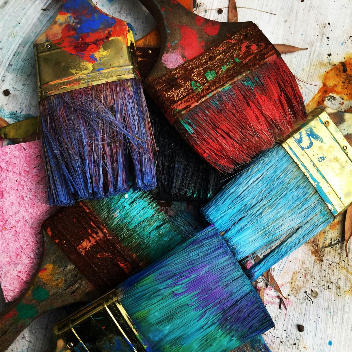 Collection of paint brushes each covered in a different colour