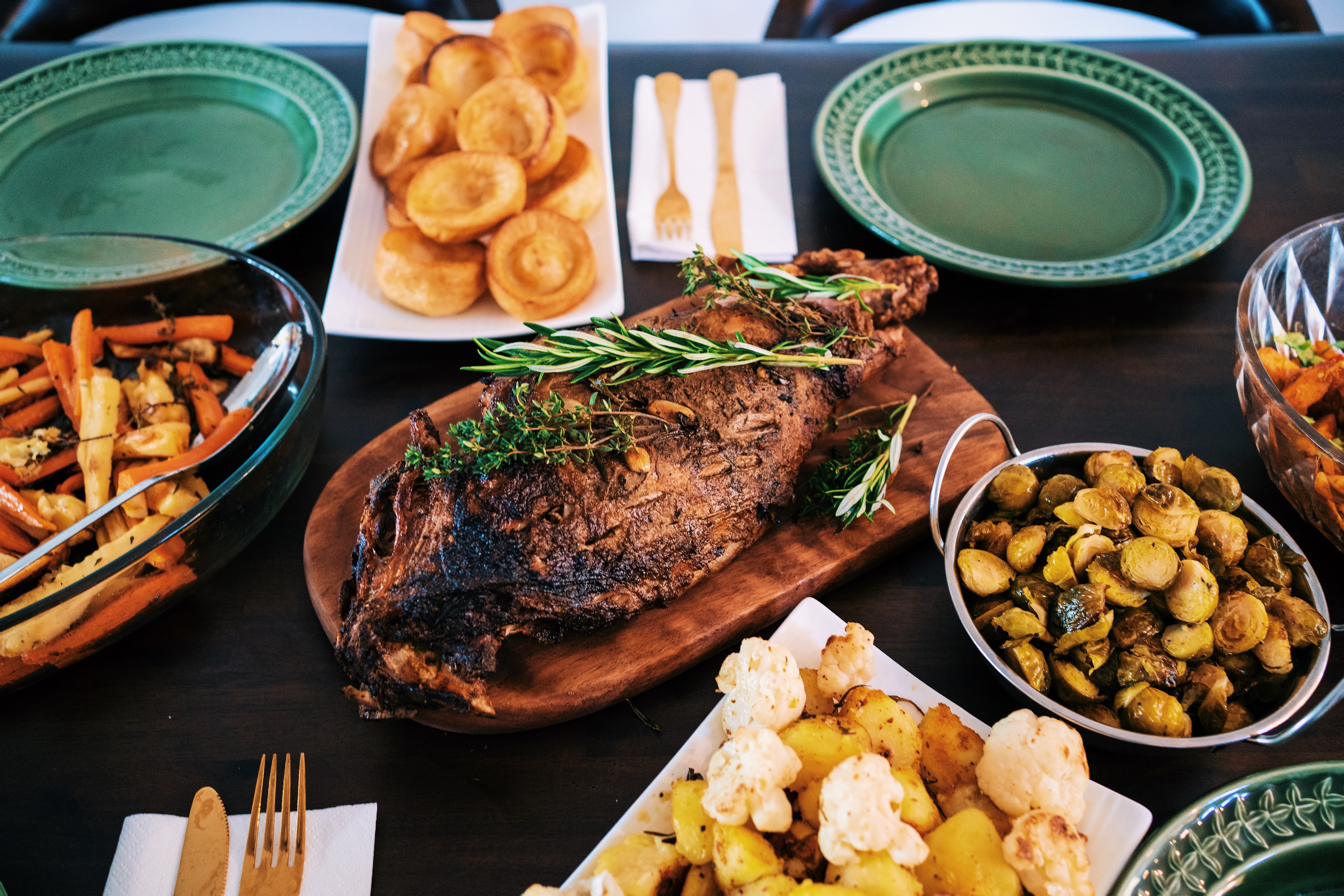 Dinner presented on serving plates, there's a joint of meat, and potatoes.
