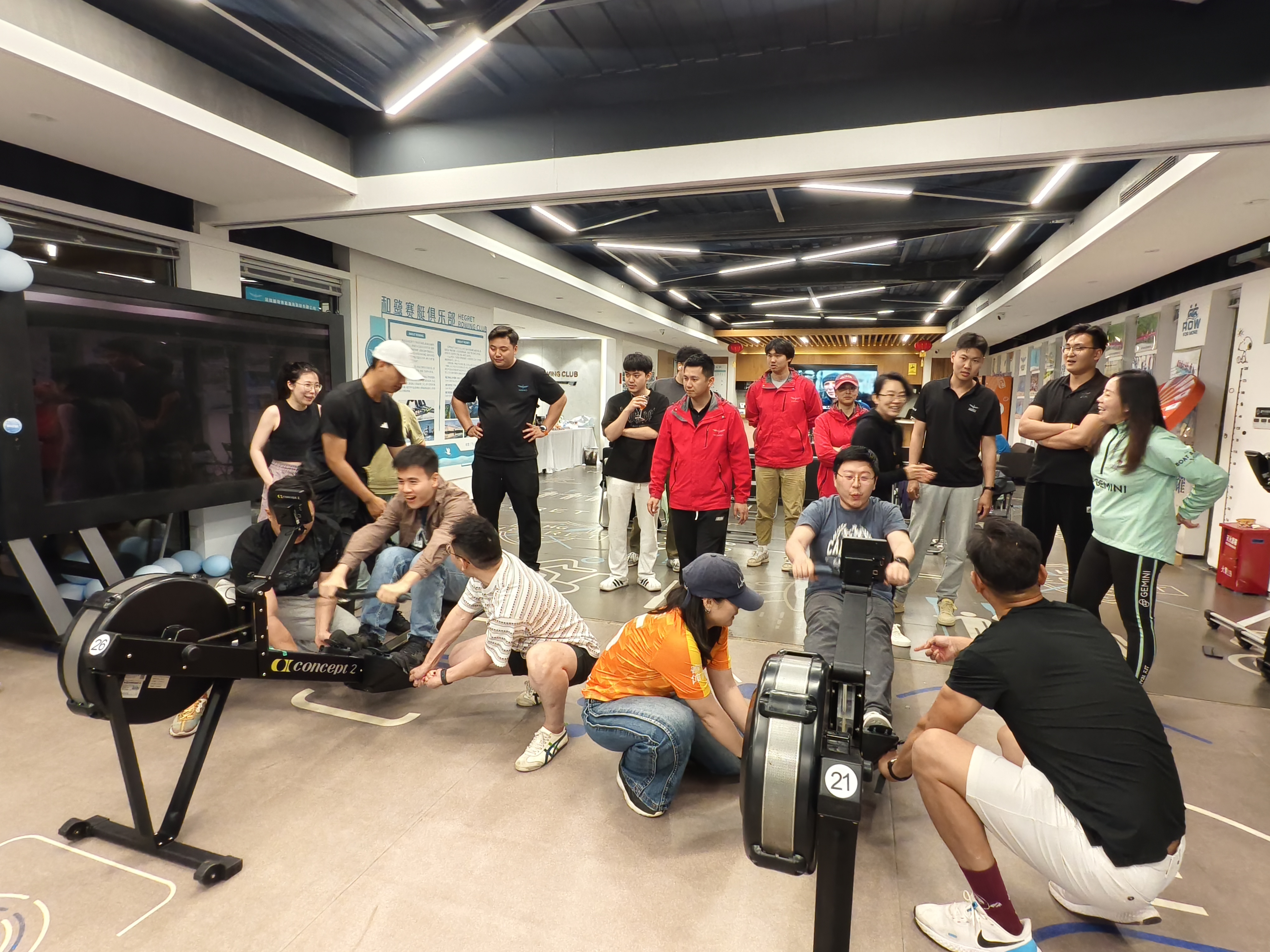 Photograph showing a group of alumni competing indoors on ergs during their official boat race event