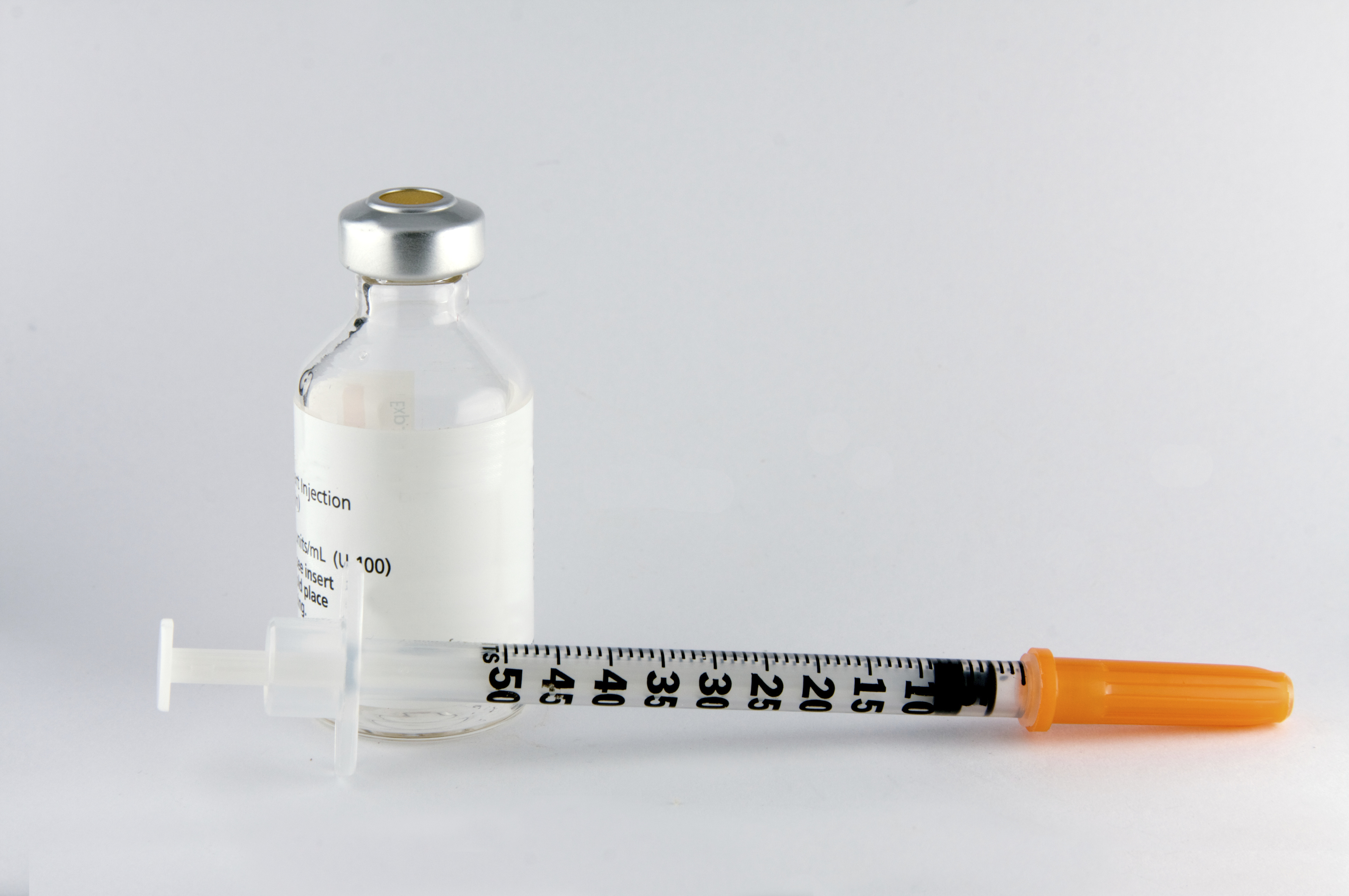 Syringe with a bottle of medication sit on a desk