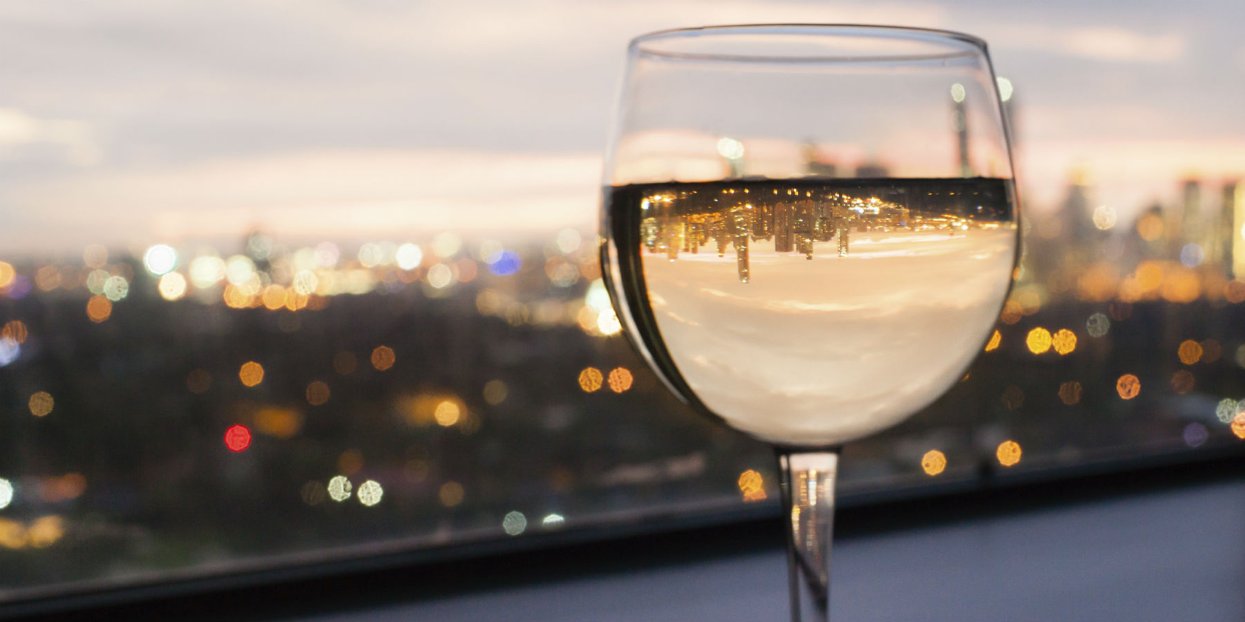Glass of white wine with a cityscape in the background at sunset
