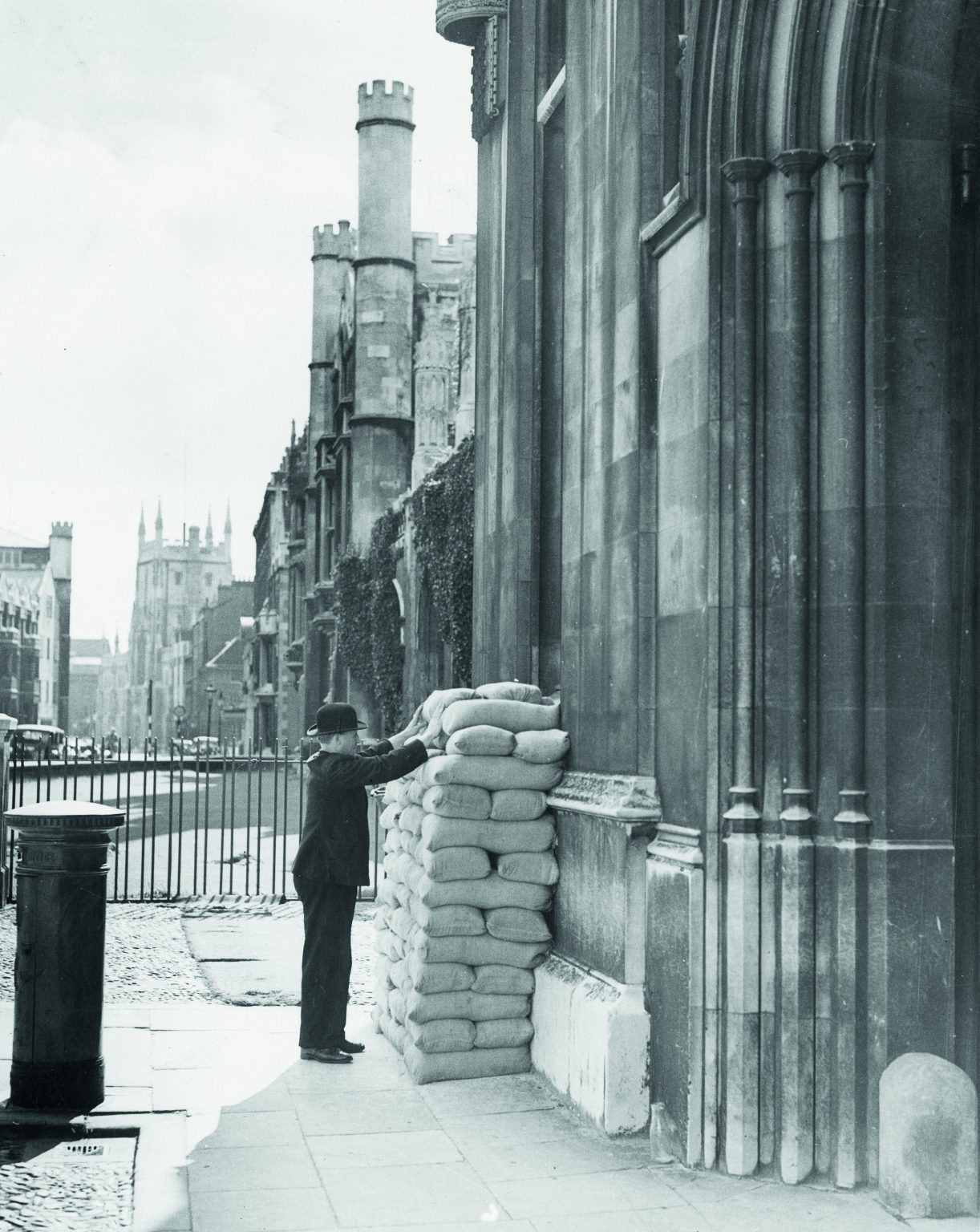 A porter checking sandbags outside a College