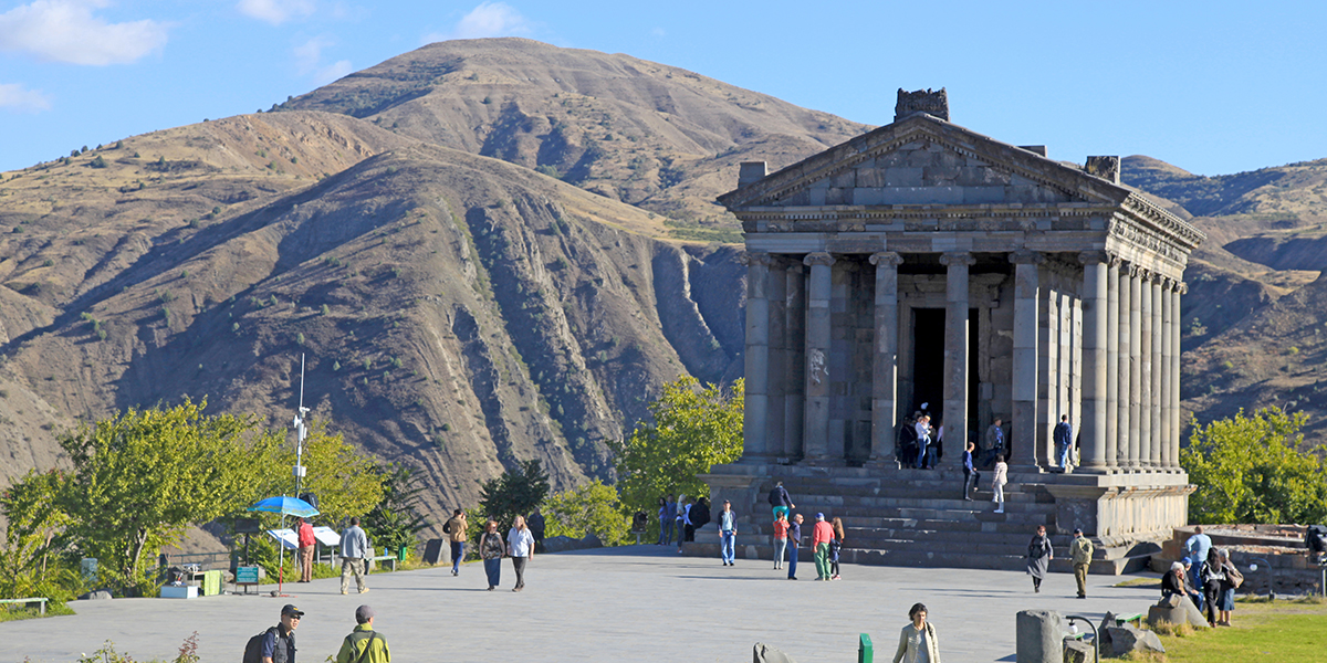 Classical colonnaded structure in the village of Garni, surrounded by grass covered mountains
