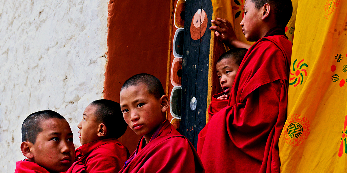 Five Bhutan monks, dressed in red robes looking out to the distance