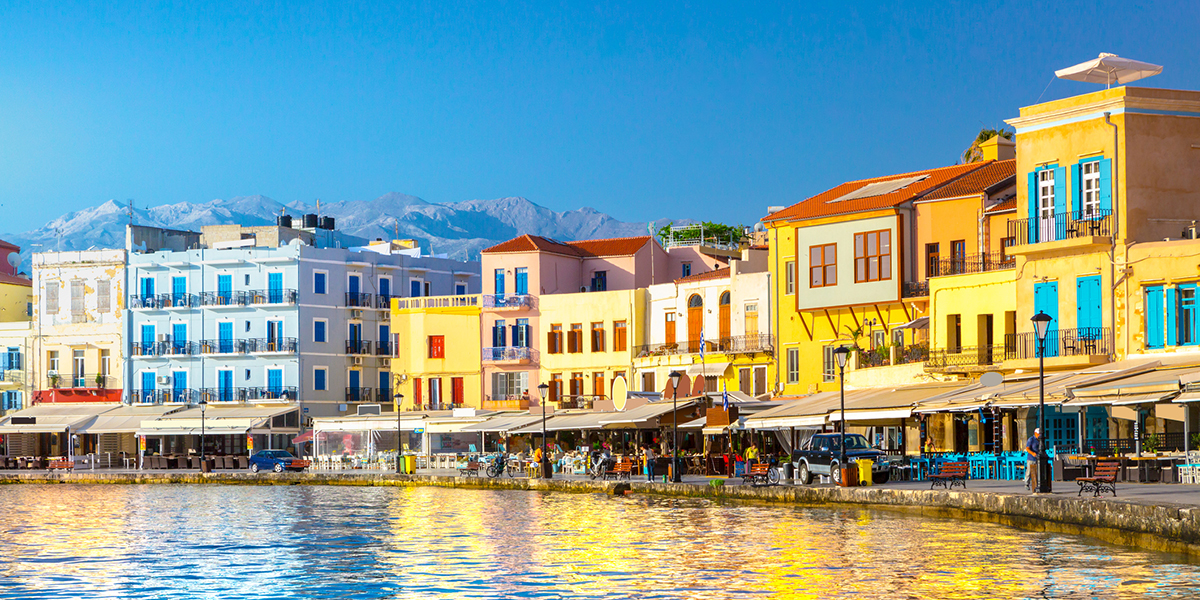 Row of colourful buildings along a lake sore, with a clear blue sky