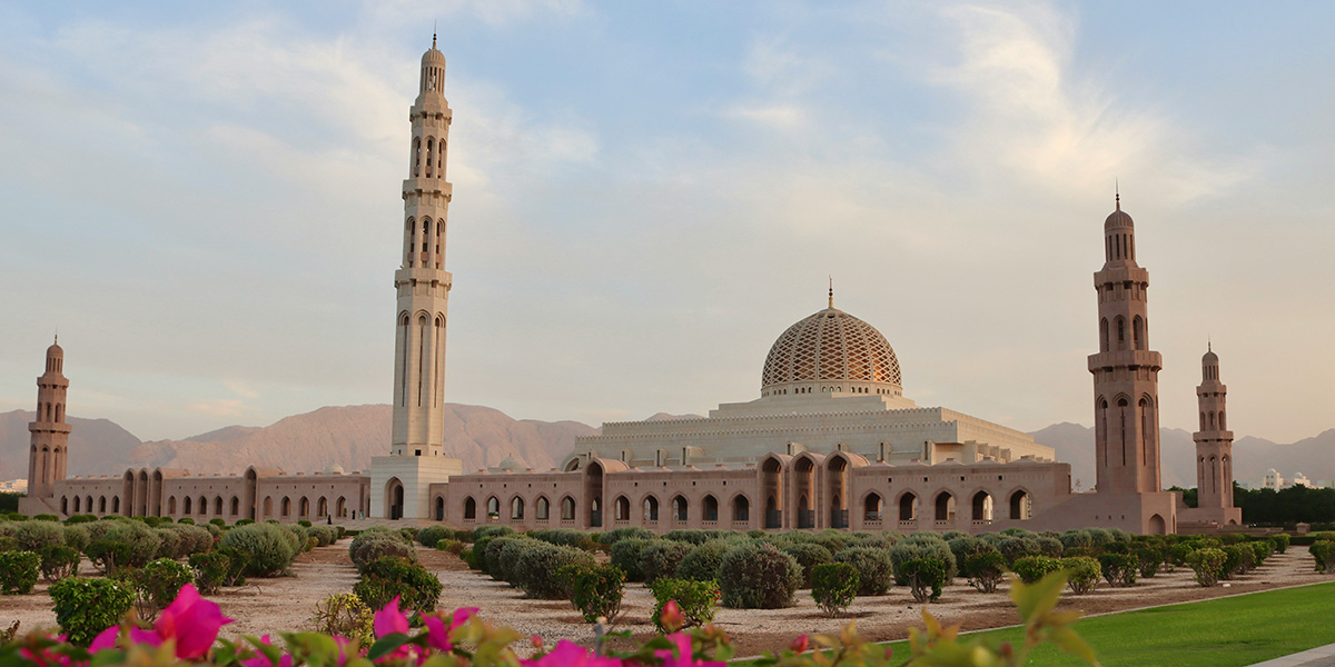 ultan Qaboos Grand Mosque, Square single floor white building with rows of arch shaped windows with a large golden dome