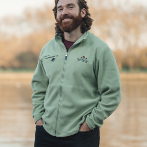 Photograph of Seb Benzecry wearing Cambridge blue Cambridge University Boat Club fleece by the river