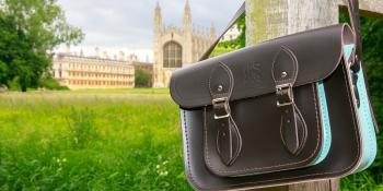 Brown leather satchel hanging on a woodne post with King's College across the green in the background