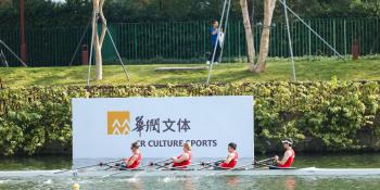 Four rowers pass the sign advertising the Shenzhen event in a boat
