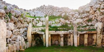 Neolithic temples in Malta, four squares entrances with boulders piled above with grass growing over the boulders