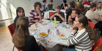 A group of freshers at a table talking and eating snacks
