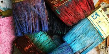Collection of paint brushes each covered in a different colour