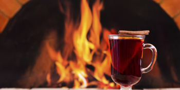 A glass of mulled wine in front of a roaring fire