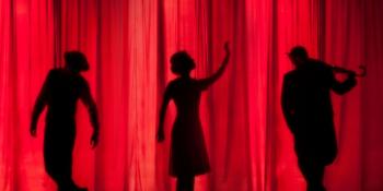 Three actors on a stage in front of a red curtain