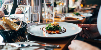 photo of a dinner plate containing a nicely presented main dish, a woman's hand is holding the edge of the plate