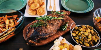Dinner presented on serving plates, there's a joint of meat, and potatoes.