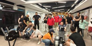 Photograph showing a group of alumni competing indoors on ergs during their official boat race event