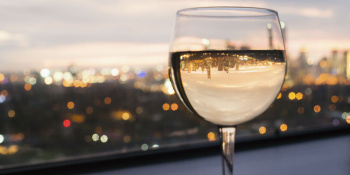 Glass of white wine with a cityscape in the background at sunset