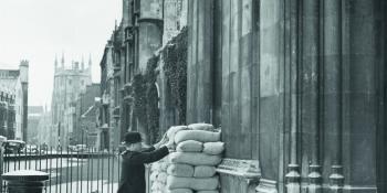 A porter checking sandbags outside a College