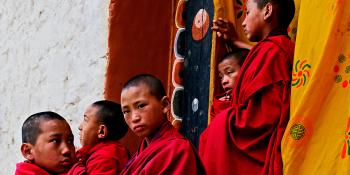 Five Bhutan monks, dressed in red robes looking out to the distance