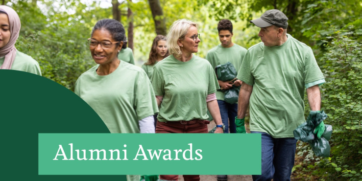 People in green t-shirtd walking through a wooded area