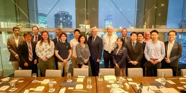 Large group of people in business formal attire stood behind a large dining tableLarge group of people in business formal attire