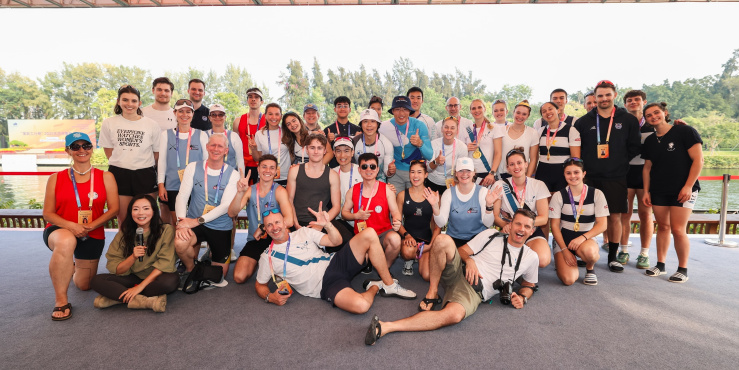 Members of the alumni groups gather for a group photo, they are smiling and showing peace hand gestures