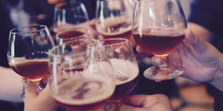 Beer glasses being held by a group of people saying cheers.