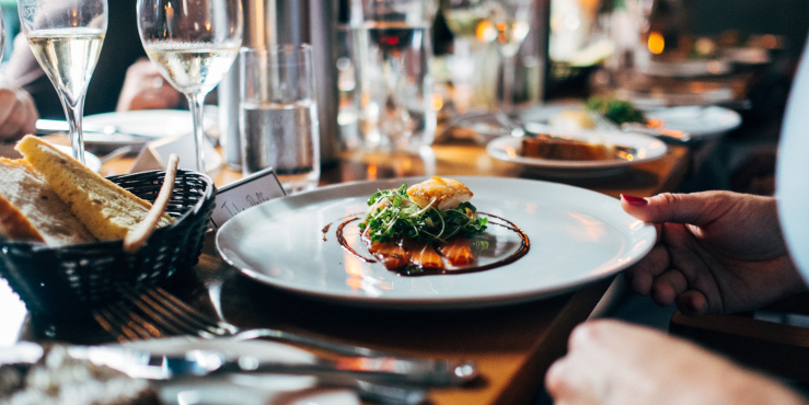 photo of a dinner plate containing a nicely presented main dish, a woman's hand is holding the edge of the plate