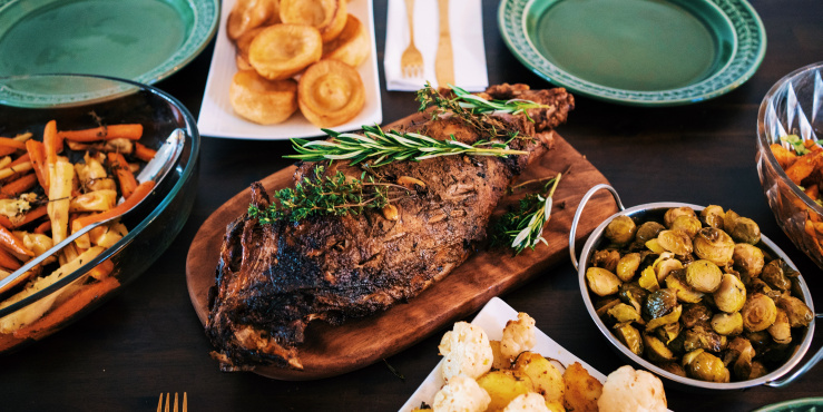 Dinner presented on serving plates, there's a joint of meat, and potatoes.