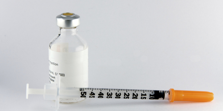 Syringe with a bottle of medication sit on a desk