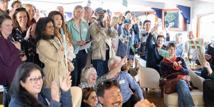 A crowd cheers and waves flag in celebration of the Boat Race