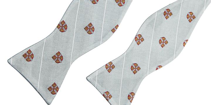 Alumni bow tie with University shields on the background of Cambridge blue