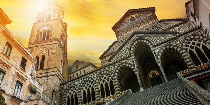 Up looking photo of the cathedral Sant Andrea with yellow sunlight beaming down from the left