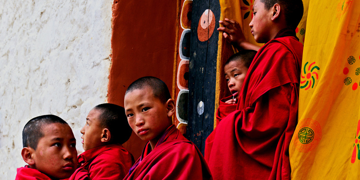 Five Bhutan monks, dressed in red robes looking out to the distance