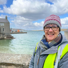 Margaret Cooper in Shetland standing next to the blue clear sea