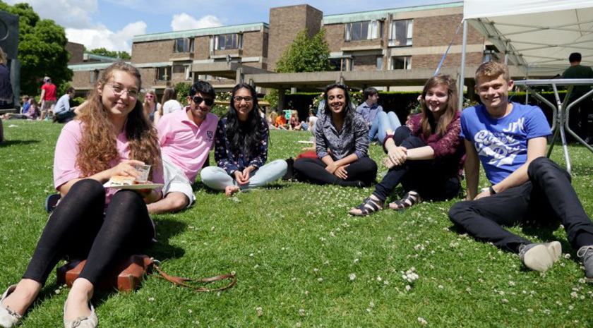 Students at Churchill College sitting in a group on the lawn