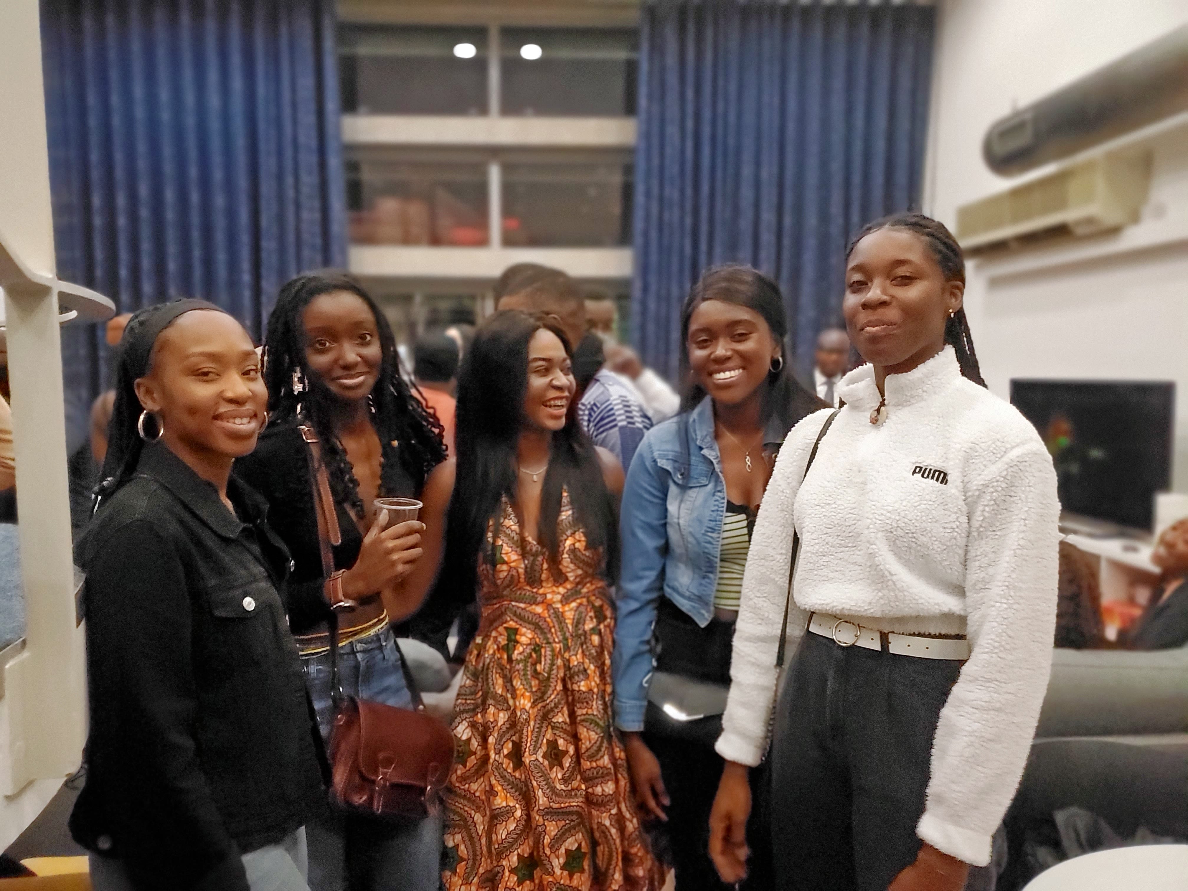 A group of five African students pose in line, laughing.