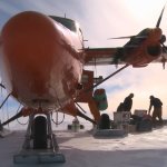 A plane sits in a snowy landscape while researchers unload cargo