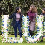Image of people standing in front of floral working 'Lucy'