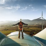 Man standing on top of a wind turbine with CJBS logo in top left corner