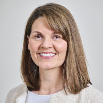 Portrait photograph of a woman with brown hair against a grey background