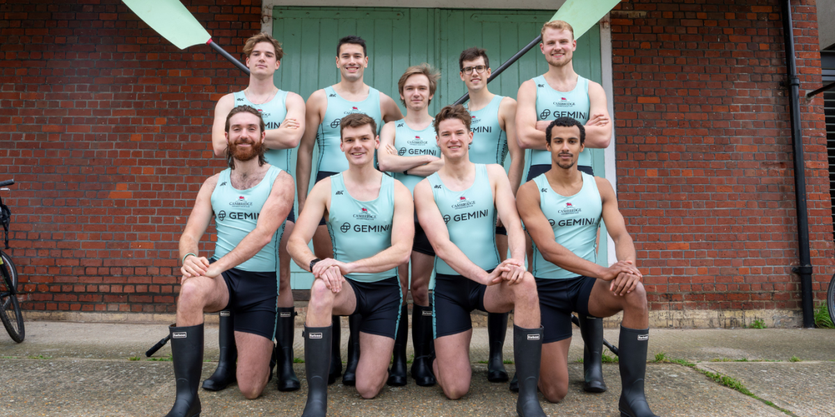 The Cambridge Men's Blue Boat Crew are pictured together in two lines. The front row kneel, whilst the back row stand.