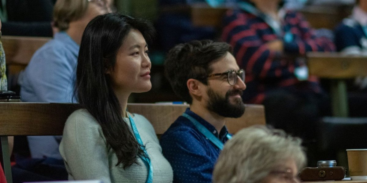 A man and woman sit in an auditorium listening to a lecture.