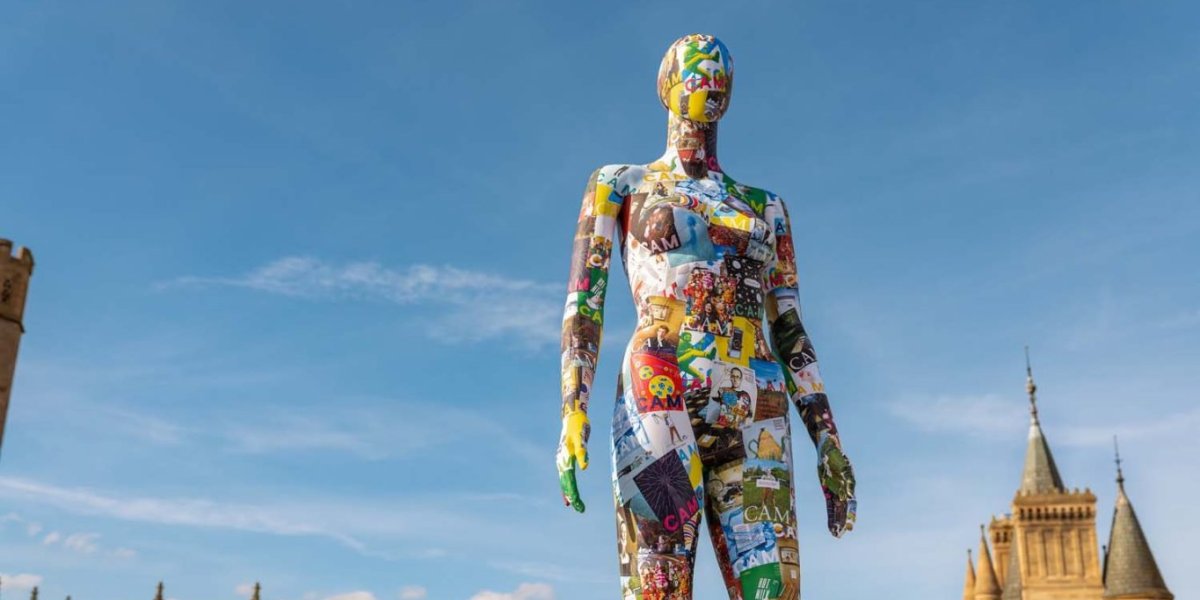 The CAM mannequin stands against a blue sky.