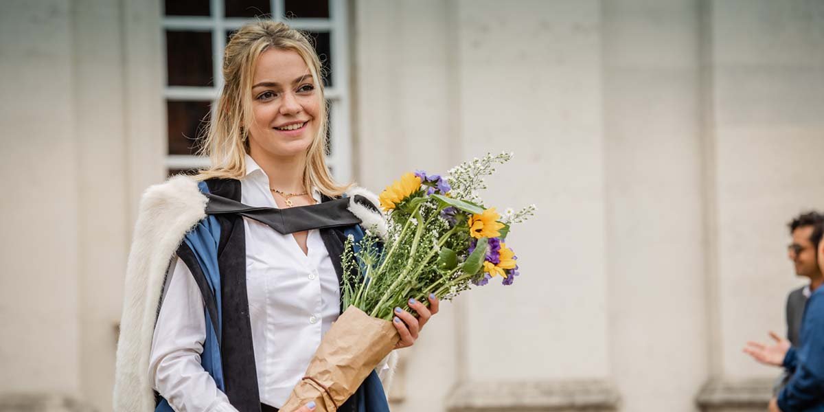 A graduate carries flowers